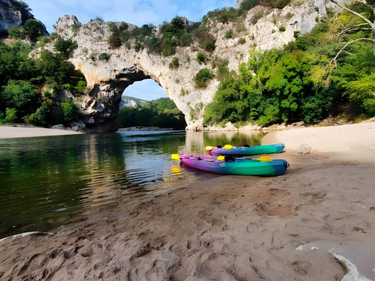 Deux canoës garés sur la plage avec vue sur le pont d'arc en arrière plan