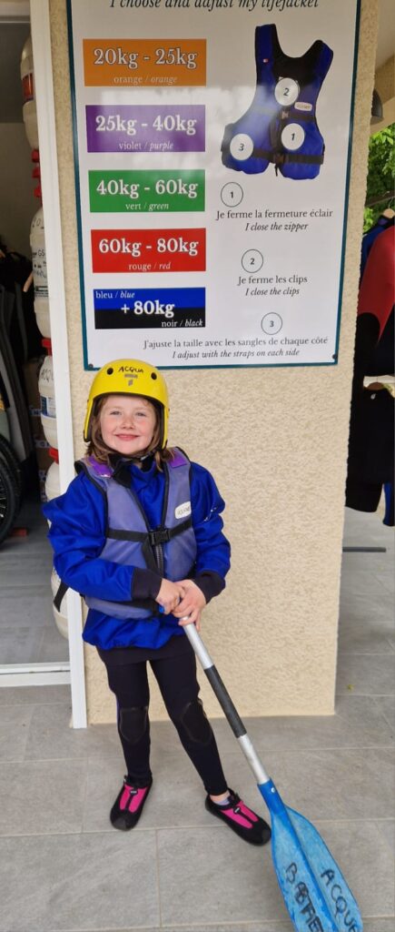 Jeune fille avec une tenue complète de Canoë, casque, pagaie et gilet de sauvetage, prête à descendre les gorges de l'Ardèche.